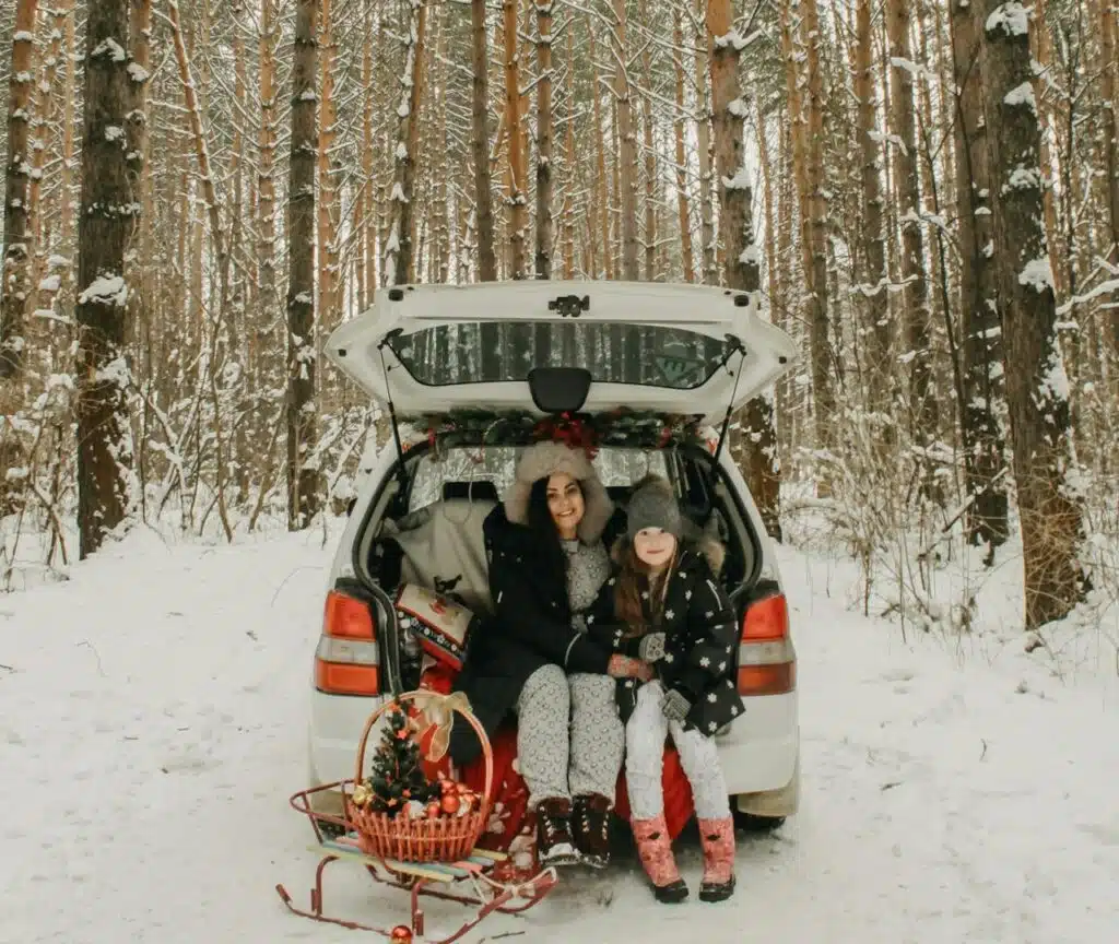 A young family sitting in the back of their vehicle. 