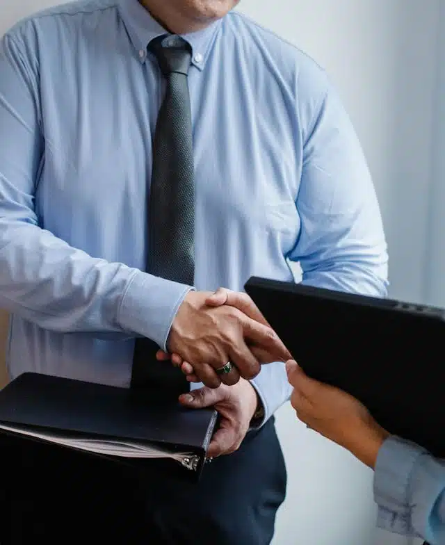 A lender shaking hands with a loan applicant in a professional setting. 